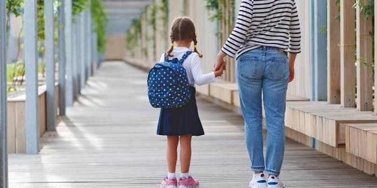 Γονέας συνοδεύει το παιδί του στο σχολείο κρατώντας το χέρι του